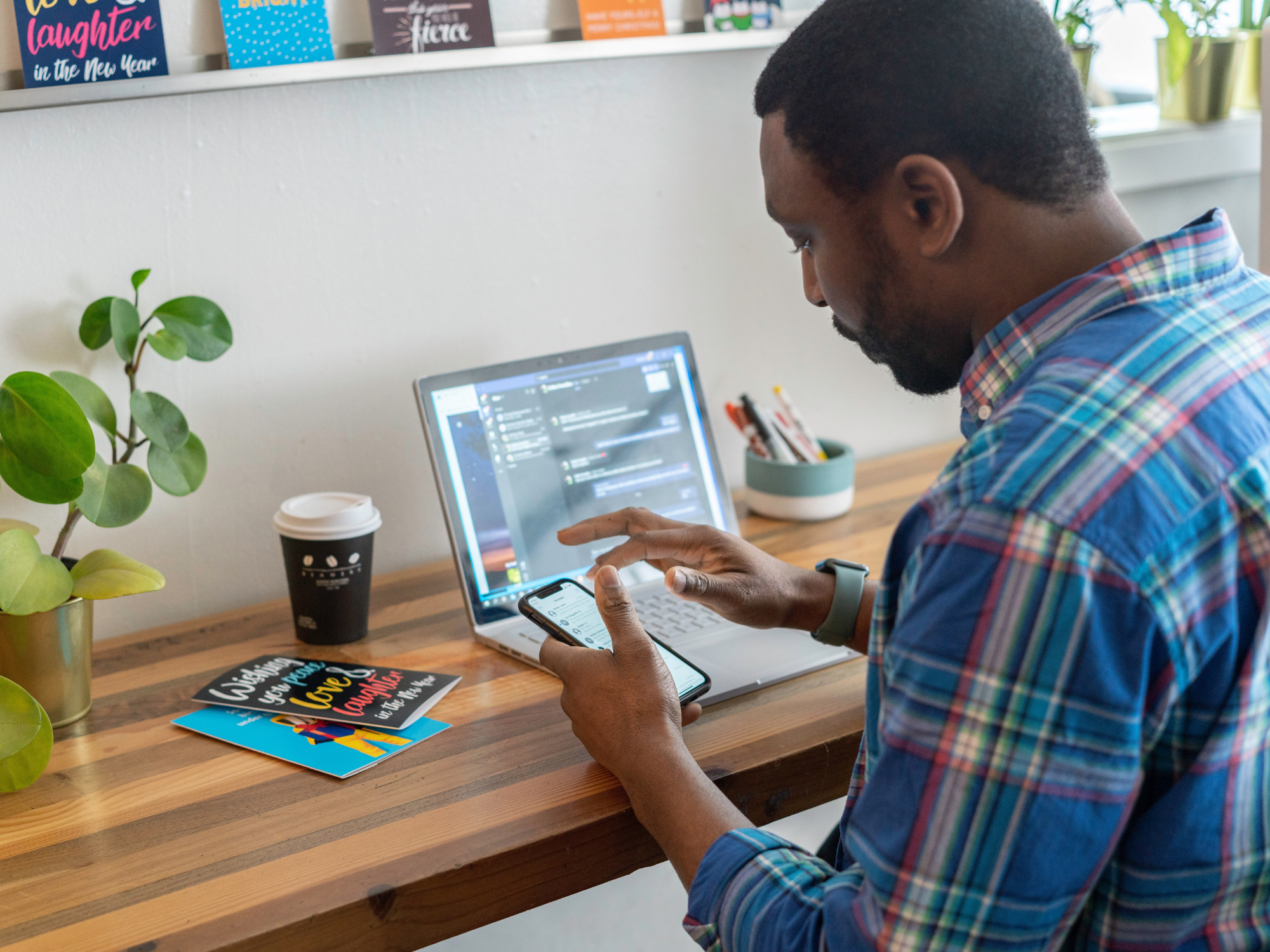 Mann mit Handy in der Hand und Laptop vor sich